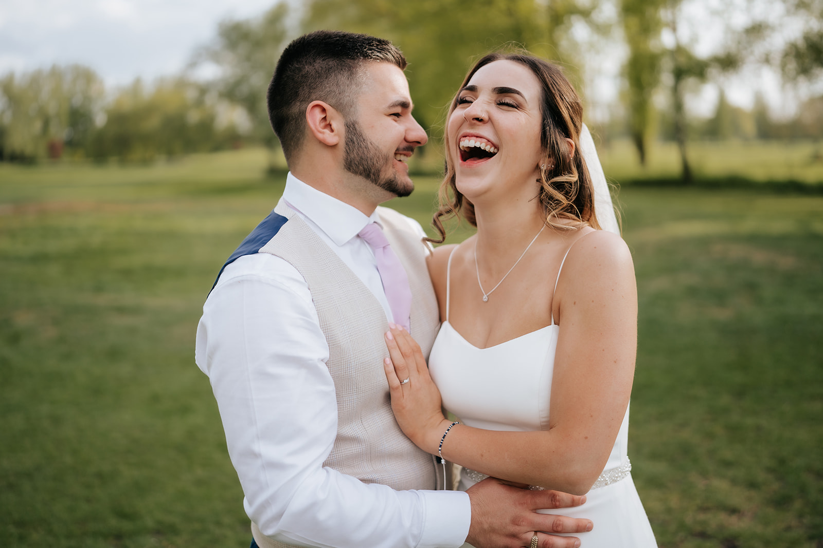 Gabby and Lewis laughing together at All Saints Golf Club in Ely on their wedding day, photographed by Tel, Lily & White Photography